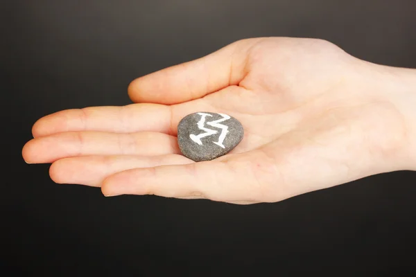 Fortuna con símbolos en piedra en la mano sobre fondo gris — Foto de Stock