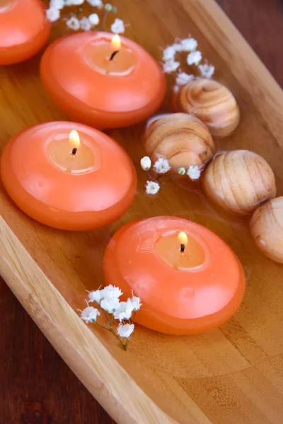 Beautiful candles in water on wooden table close-up — Stock Photo, Image