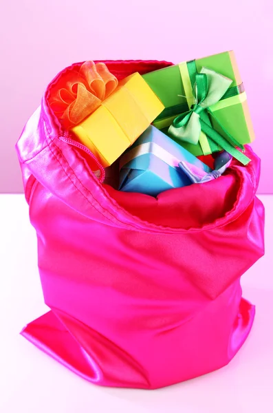 Bolso rosa con regalos sobre fondo rosa — Foto de Stock