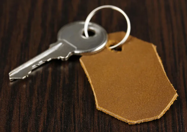 Key with leather trinket on wooden background — Stock Photo, Image