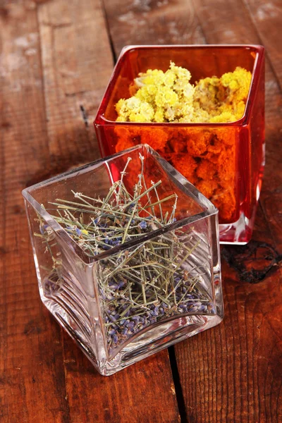 Ervas secas em recipientes de vidro na mesa de madeira close-up — Fotografia de Stock