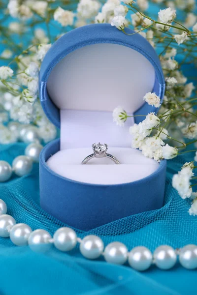 Flores y anillo de compromiso en tela azul — Foto de Stock