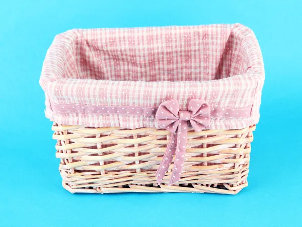 Wicket basket with pink fabric and bow, on color background — Stock Photo, Image