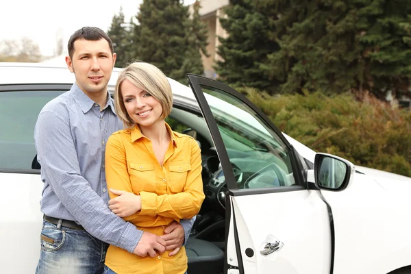 Retrato de feliz hermosa pareja de pie cerca del coche —  Fotos de Stock