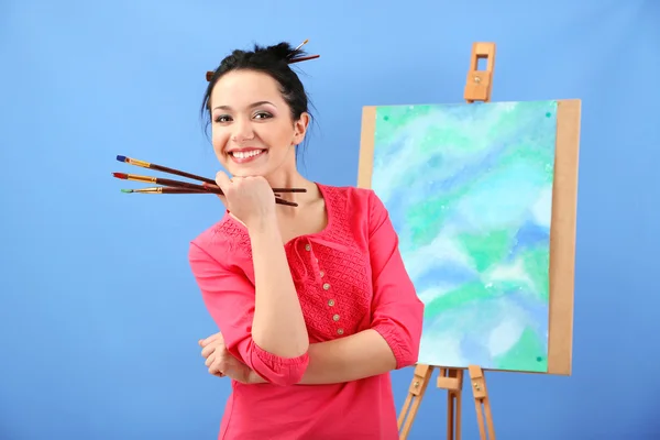 Mooie jonge vrouw schilder op het werk, op een achtergrond met kleur — Stockfoto