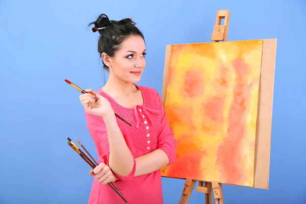 Bella giovane pittrice al lavoro, su sfondo a colori — Foto Stock