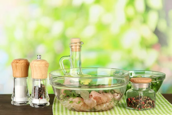 Chicken meat in glass bowl,herbs and spices on table on nature background — Stock Photo, Image