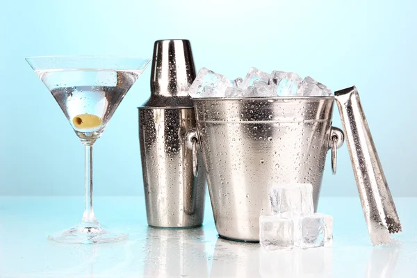Metal ice bucket and shaker and cocktail on blue background — Stock Photo, Image