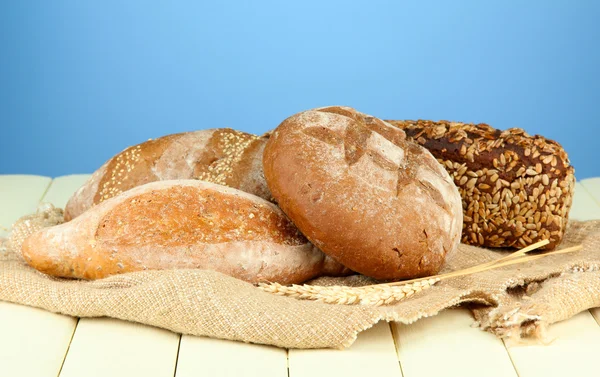 Композиція з хлібом і мішковиною на дерев'яному столі, на кольоровому фоні — стокове фото