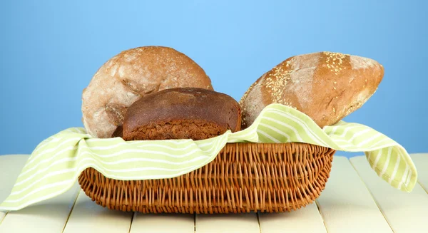 面包在柳条篮子，木制桌上，对颜色背景 — 图库照片