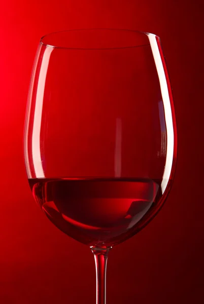 Glas Wein auf leuchtend rotem Hintergrund — Stockfoto