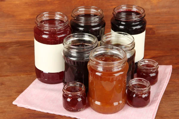 Tasty jam in banks on wooden background — Stock Photo, Image