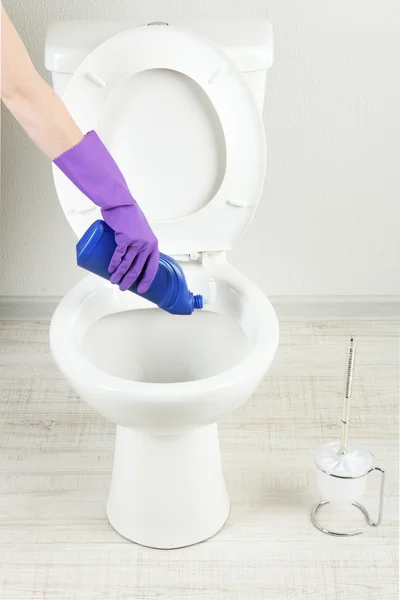 Woman hand with spray bottle cleaning a toilet bowl in a bathroom — Stock Photo, Image