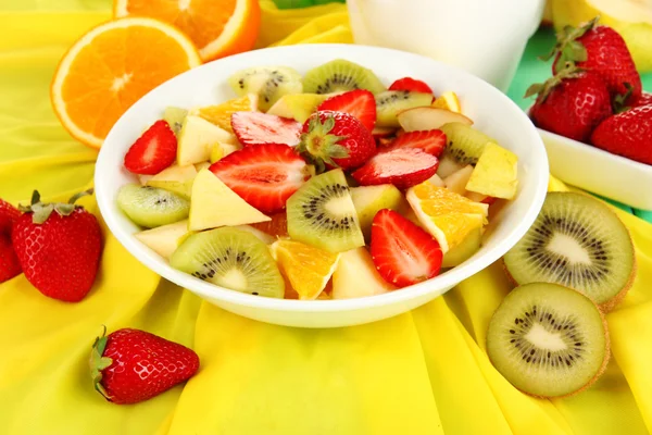 Useful fruit salad of fresh fruits and berries in bowl on tablecloth close-up — Stock Photo, Image