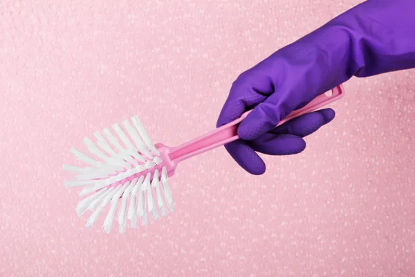 Toilet brush in hand on pink background — Stock Photo, Image