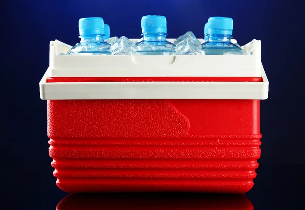 Refrigerador viajero con botellas de agua y cubitos de hielo, sobre fondo azul — Foto de Stock