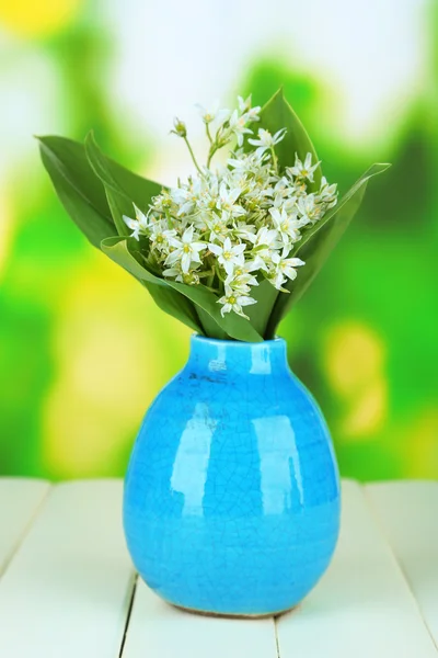 Hermosos narcisos de montaña en jarrón de color, sobre mesa de madera sobre fondo brillante —  Fotos de Stock