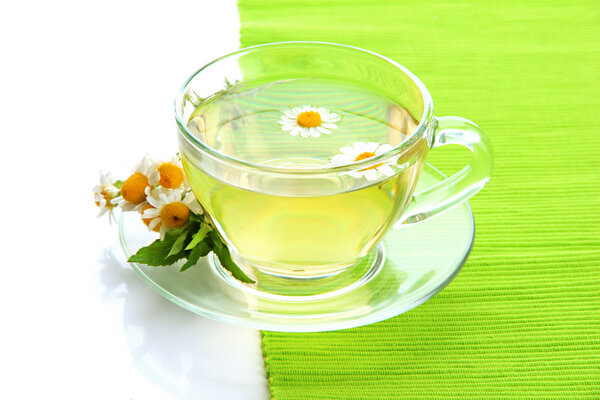 Чашка травяного чая с дикими ромашками и мятой, изолированные на белом
