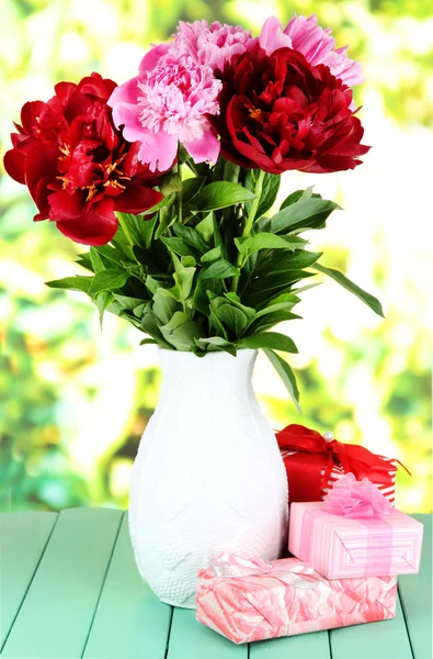Belle peonie in vaso su tavolo su sfondo luminoso — Foto Stock