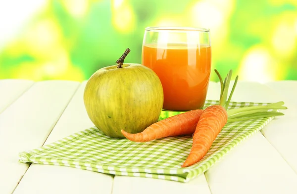 Un mucchio di carote e mela verde, vetro di succo, su tavolo di legno a colori su sfondo brillante — Foto Stock