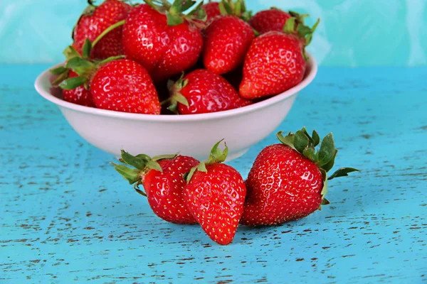 Strawberries in plate on blue background — Stock Photo, Image