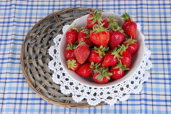 Strawberries in plate on wicker stand on napkin close-up — Stock Photo, Image