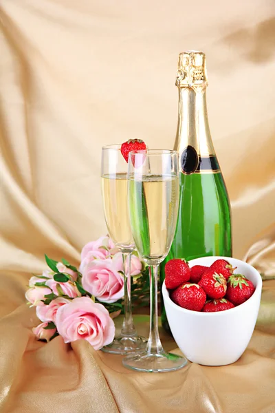 Romantic still life with champagne, strawberry and pink roses, on color fabric background — Stock Photo, Image