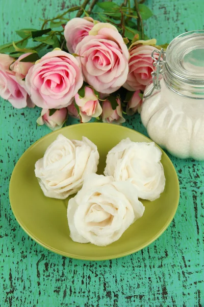 Zuckerrosen und natürliche Rosen, Glas mit Zucker, auf farbigem Hintergrund — Stockfoto