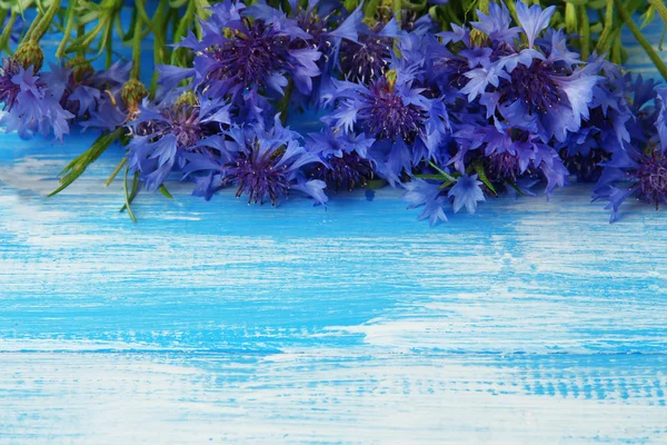 Schöner Strauß Kornblumen auf blauem Holzhintergrund — Stockfoto