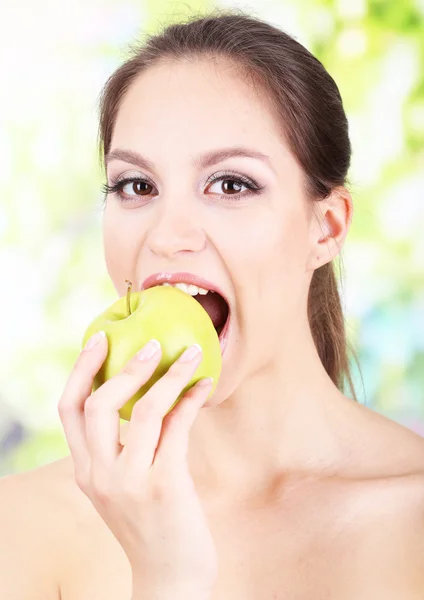 Ung kvinna med äpple på ljus bakgrund — Stockfoto