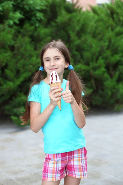 Niña patina comiendo sabroso helado en el fondo del parque —  Fotos de Stock