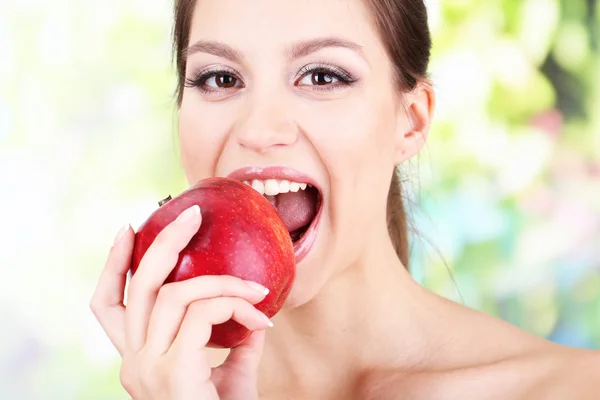 Молодая женщина с яблоком на ярком фоне — стоковое фото
