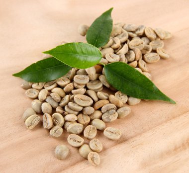 Yeşil kahve çekirdekleri ve ahşap arka plan yapraklarda