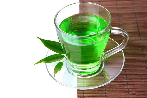 Прозрачный чашка зеленого чая на бамбуковом коврике, изолированные на белом — стоковое фото