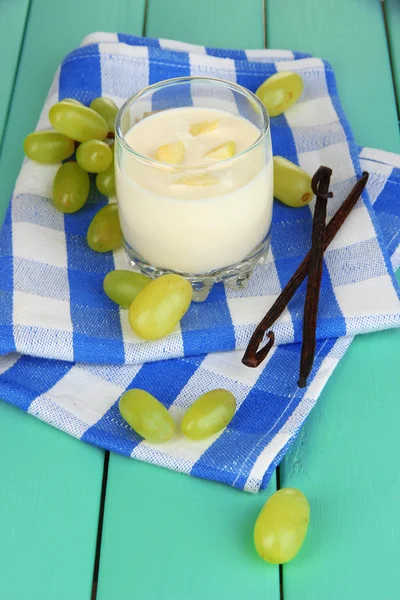 Delicious yogurt in glass with grapes on wooden table close-up — Stock Photo, Image