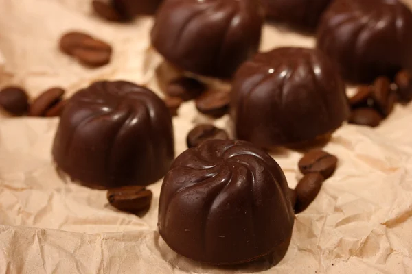 Caramelle al cioccolato e chicchi di caffè, su sfondo di carta beige — Foto Stock