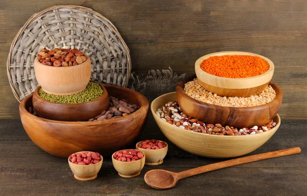 Different kinds of beans in bowls on wooden background — Stock Photo, Image