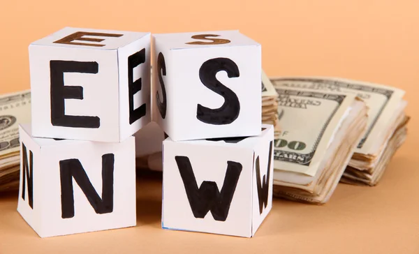 Witboek kubussen met het label "nieuws" met geld op beige achtergrond — Stockfoto