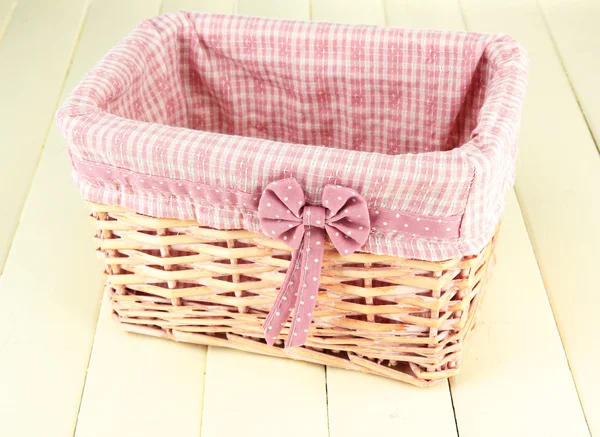 Wicket mand met roze stof en strik, op een houten achtergrond kleur — Stockfoto
