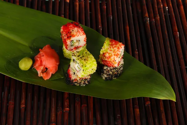 Tasty Maki sushi - Roll on green leaf on bamboo mat — Stock Photo, Image