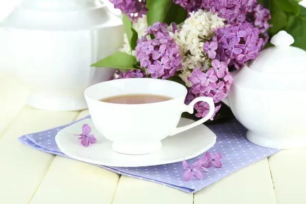 Composition with beautiful lilac flowers, tea service on wooden table, close up — Stock Photo, Image