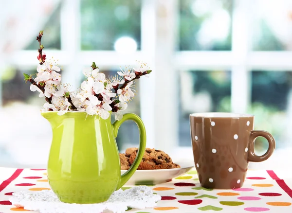 Beautiful blooming branches in pitcher on window background — Stock Photo, Image