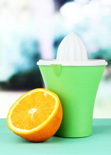 Citrus press and ripe orange on green wooden table — Stock Photo, Image