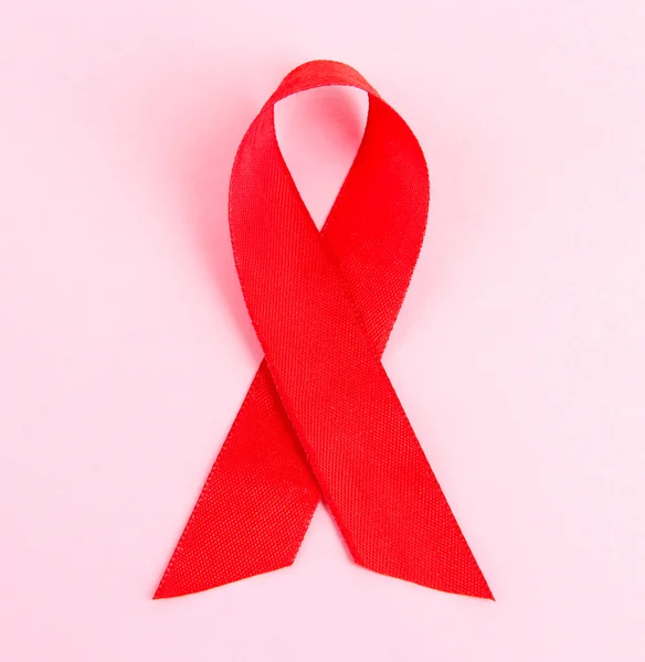 Kırmızı kurdele HIV, AIDS, pembe arka plan — Stok fotoğraf