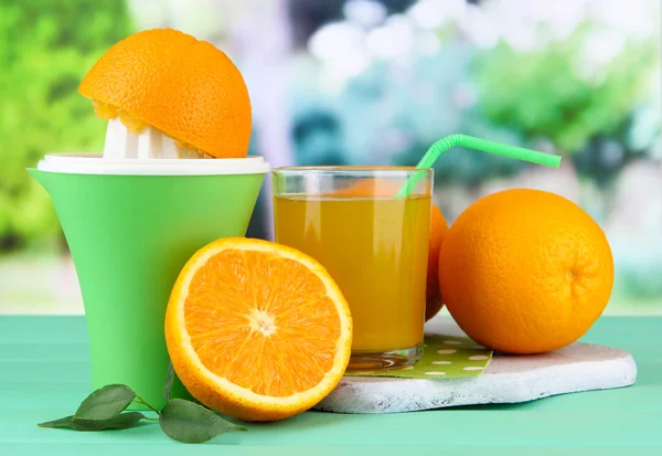 Citruspers, glas sap en rijpe sinaasappelen op groene houten tafel — Stockfoto