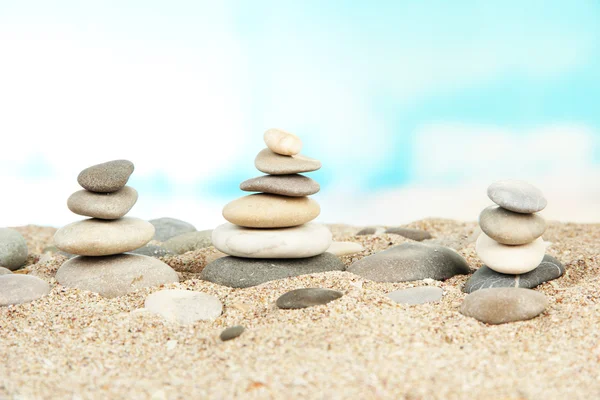 Torens van zee stenen op zand op lichte achtergrond — Stockfoto