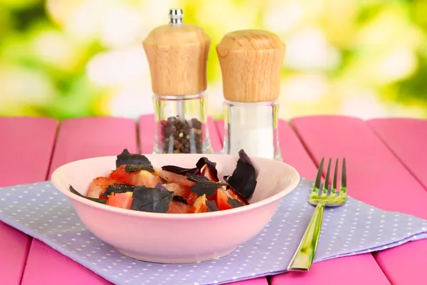 Ensalada de tomates frescos con hojas de albahaca en servilleta sobre mesa de madera sobre fondo natural — Foto de Stock