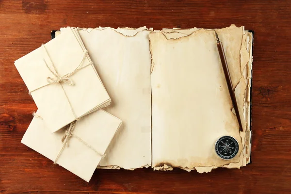 Oud boek, brieven en kompas op houten achtergrond openen — Stockfoto
