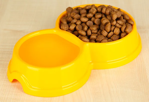 Comida seca para perros en un tazón sobre fondo de madera — Foto de Stock