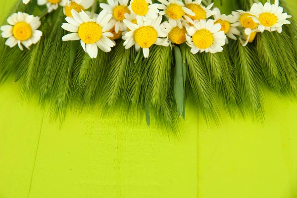 Espiguillas verdes y manzanillas silvestres, sobre fondo de madera — Foto de Stock